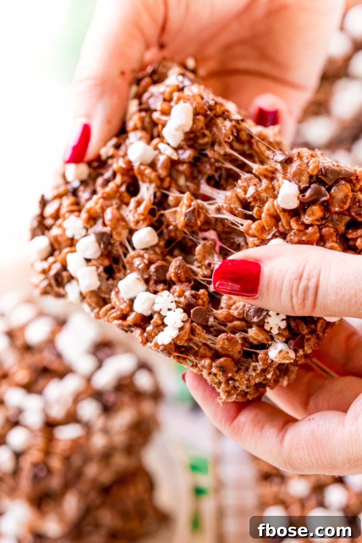 Toasty Cocoa Krispie Bars 6 A woman's hand tearing apart a chocolate rice krispie treat.