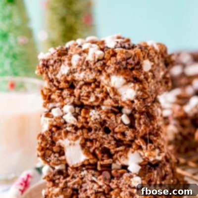 Toasty Cocoa Krispie Bars 7 Close up photo of 3 chocolate rice krispie treats stacked on top of each other on a white plate.
