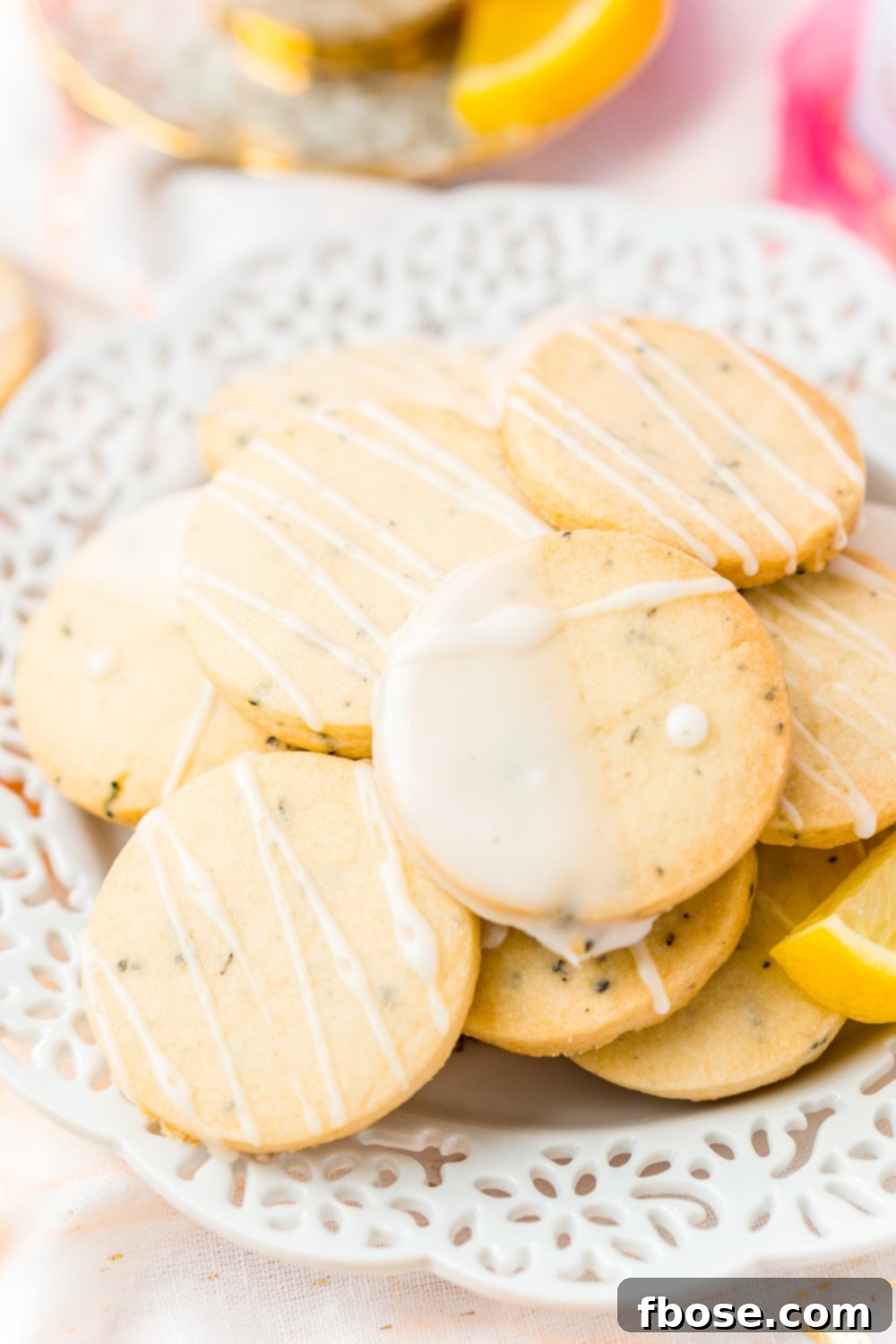 A pristine white plate holds a generous scattering of Earl Grey Shortbread Cookies, each artfully drizzled with a bright lemon glaze, ready to be enjoyed.