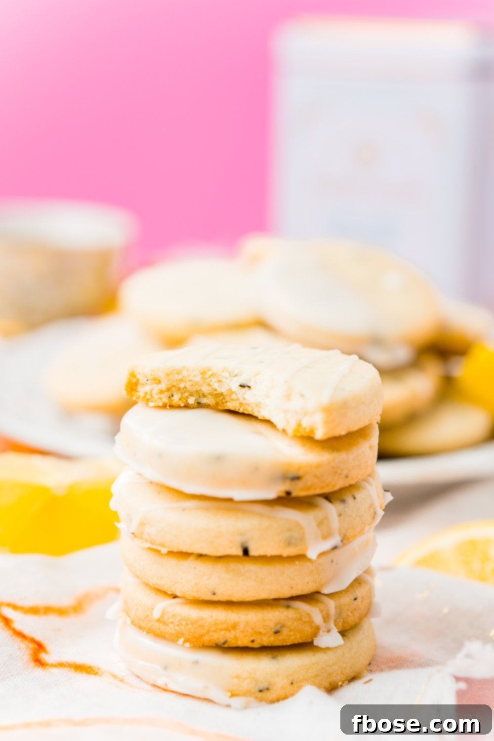 A close-up stack of golden Earl Grey Cookies, with the top cookie having a bite taken out, revealing its crumbly texture and inviting deliciousness.