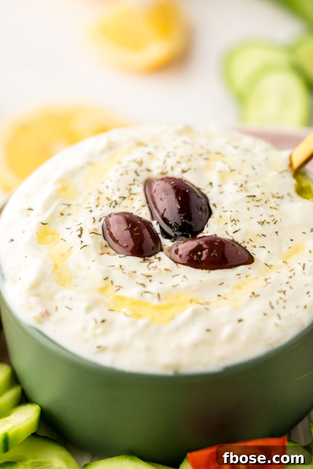 Creamy Greek Cucumber Tzatziki 2 Close up photo of a green bowl with tzatziki sauce in it.