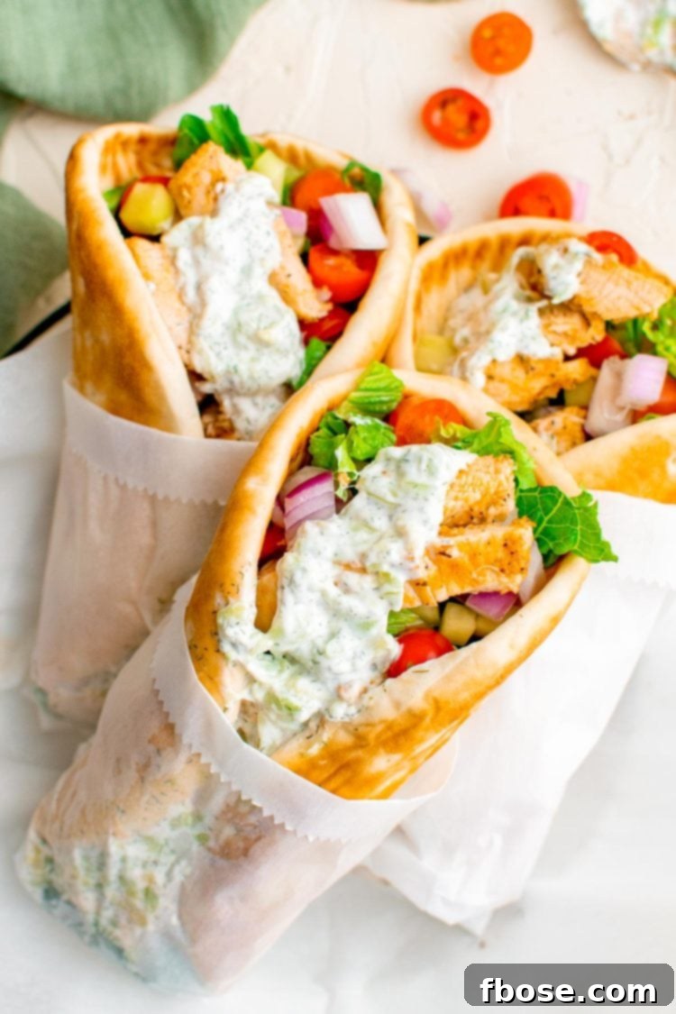 Three chicken gyros stacked up on a table.