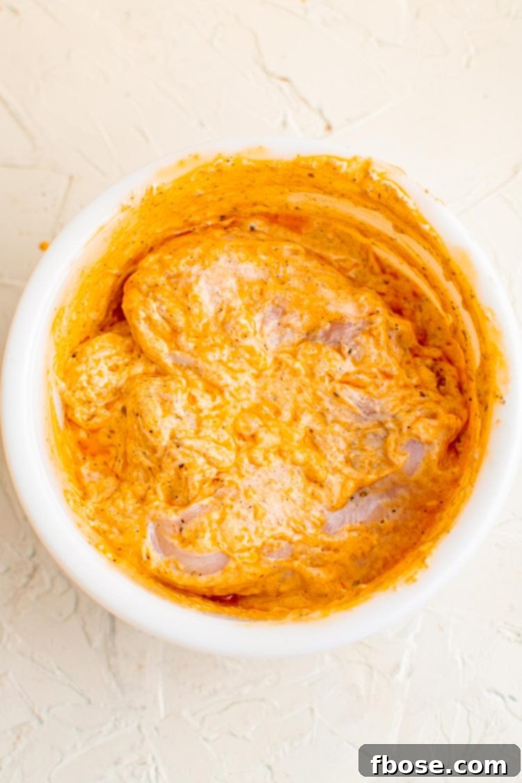Overhead photo of a bowl of chicken marinating in yogurt sauce to make chicken gyros.