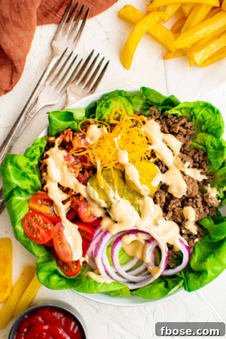 overhead photo of burger bowl with forks next to it and topped with sauce.