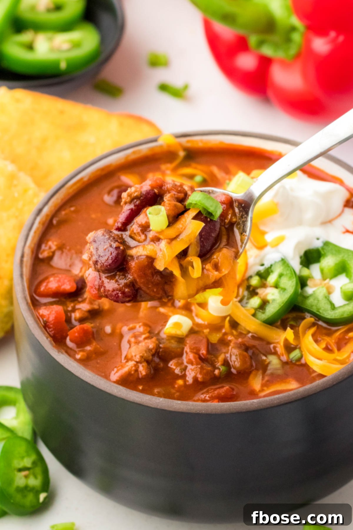 A spoonful of rich turkey chili coming out of a bowl, highlighting the hearty ingredients.