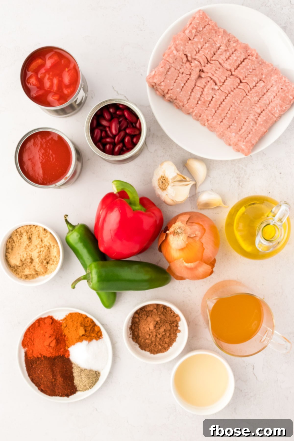 Overhead photo of fresh ingredients to make turkey chili prepped on a white counter, ready for cooking.