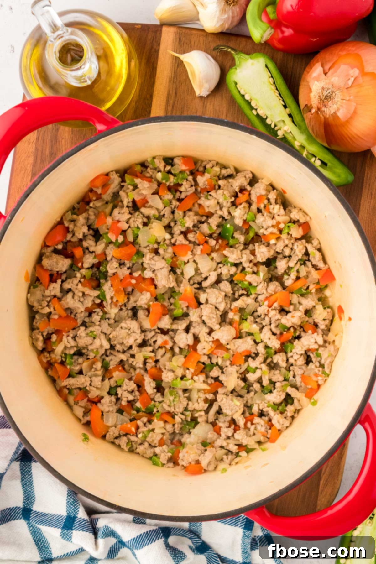 Ground turkey and vegetables being cooked together in a Dutch oven, browning evenly.