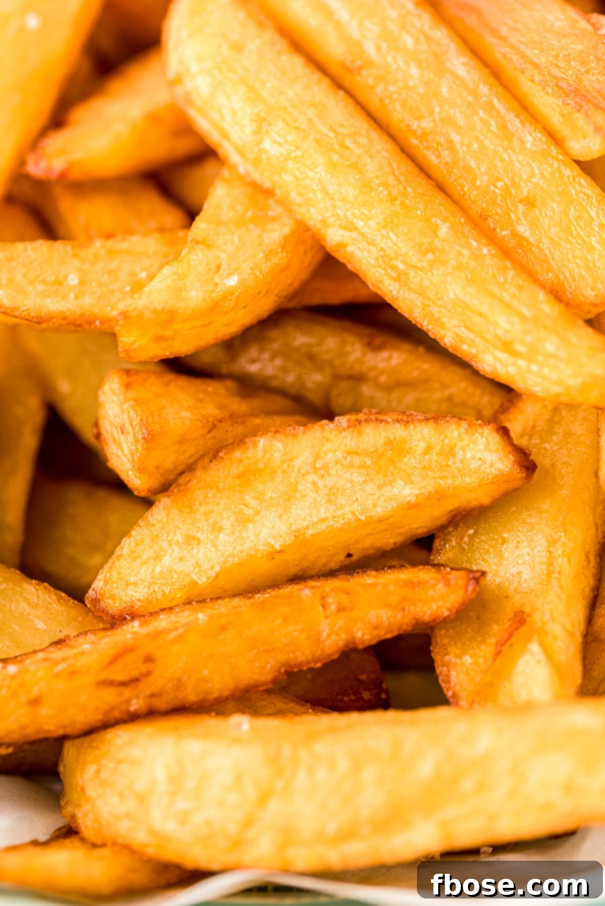 Super close up photo of freshly made, golden brown French fries.