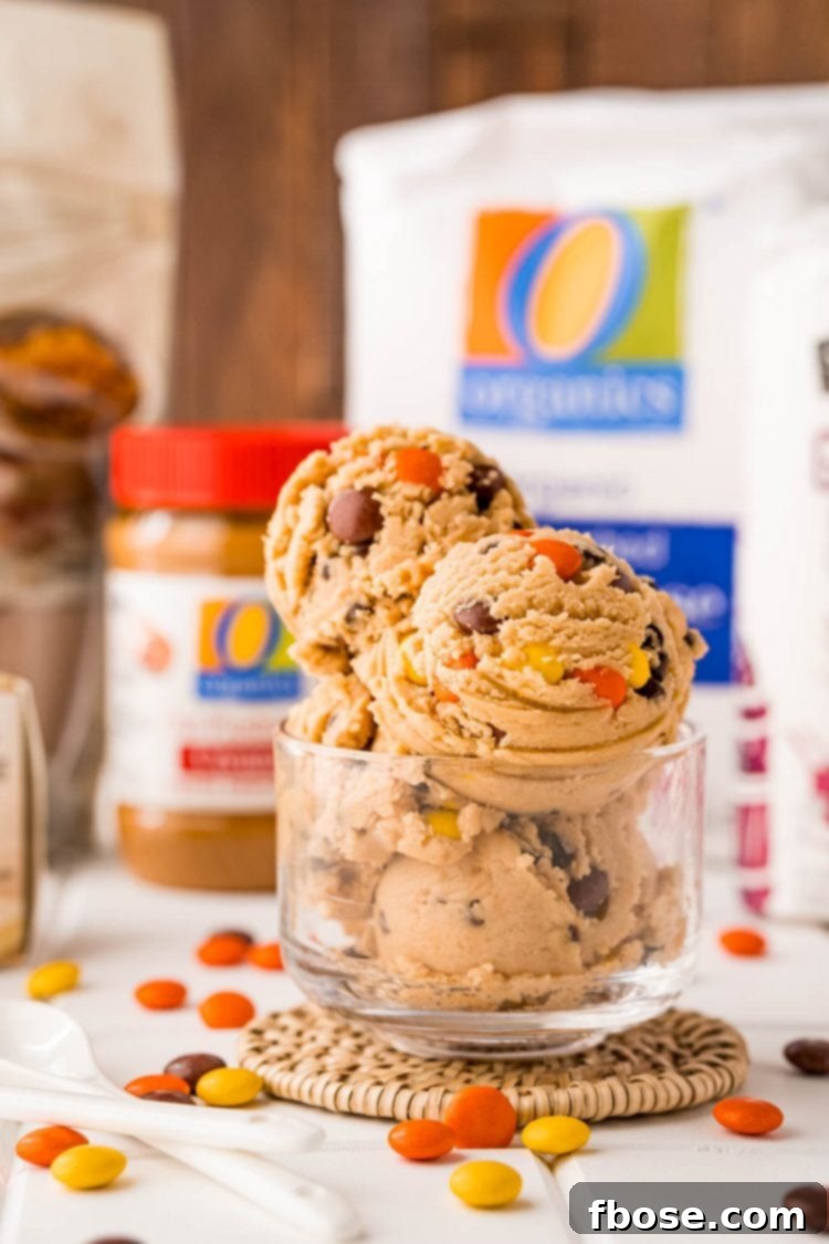 Edible peanut butter cookie dough in a glass bowl, with all the dry and wet ingredients in separate bowls behind it.