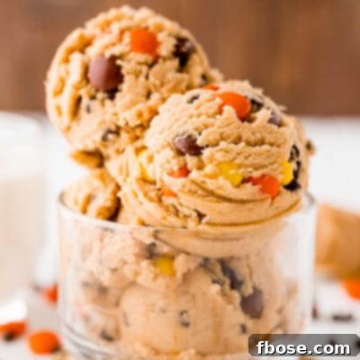 Close up photo of edible peanut butter cookie dough in a clear glass bowl, ready to be enjoyed.