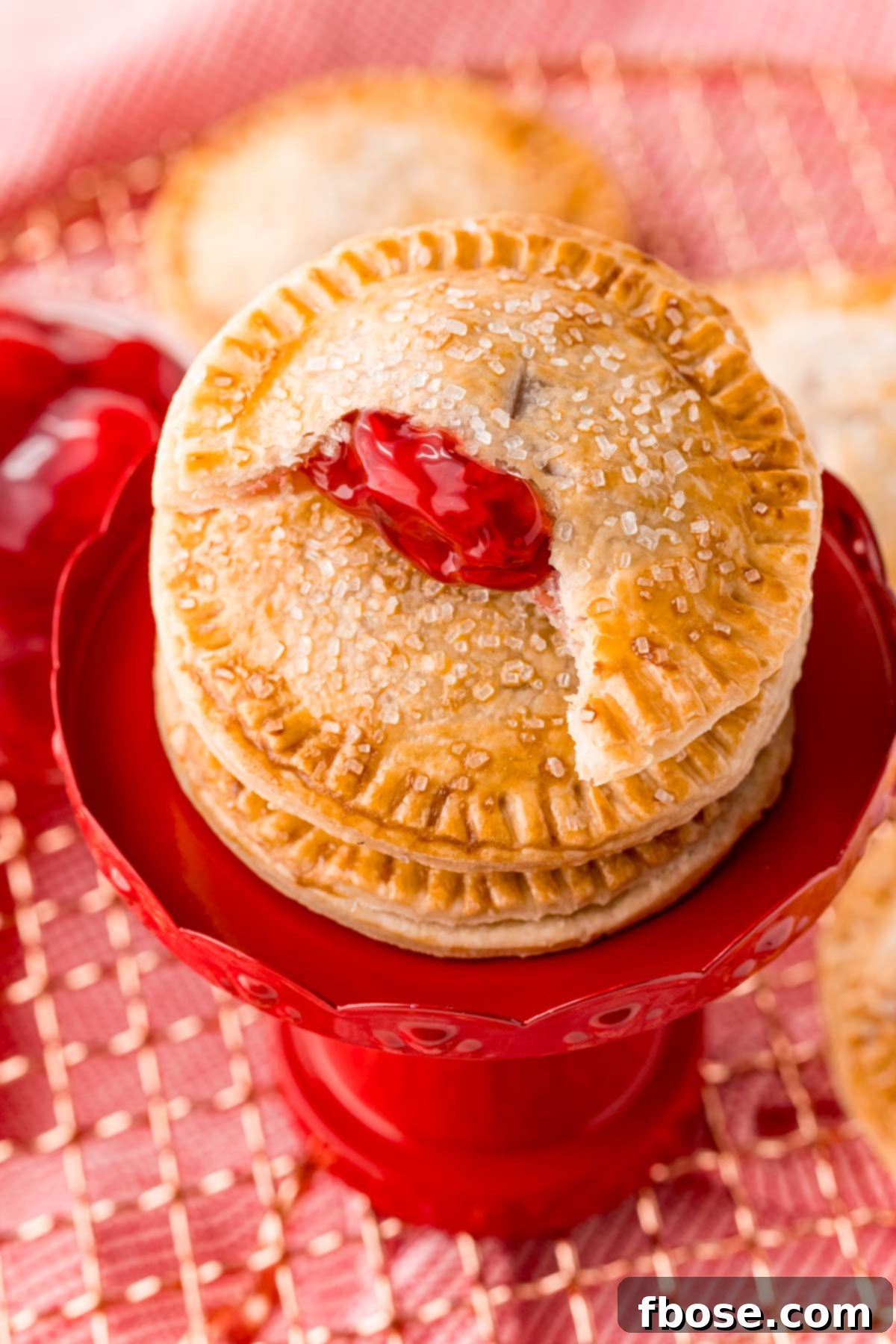 Cherry hand pies stacked on a small dessert stand. Ideal for any occasion.
