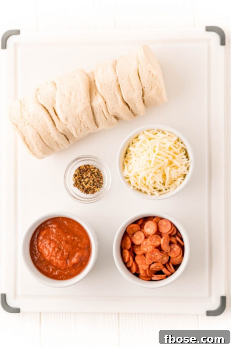 Overhead photo of ingredients to make air fryer pizzas on a white cutting board.