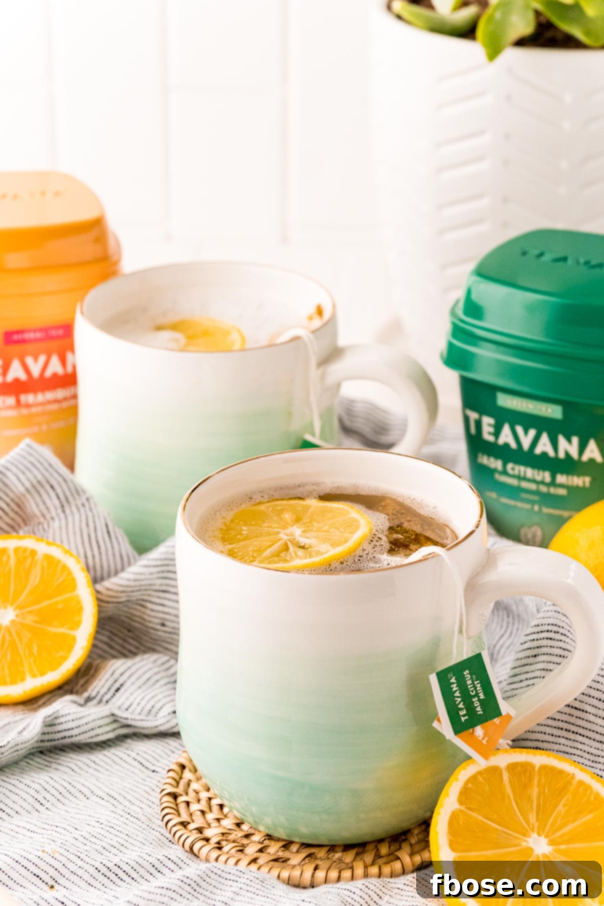 A homemade medicine ball tea on a coaster on a grey napkin with sliced lemons around it, radiating warmth.