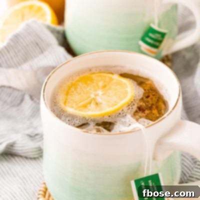 A mug filled with a homemade Starbucks medicine ball tea, garnished with a lemon slice.