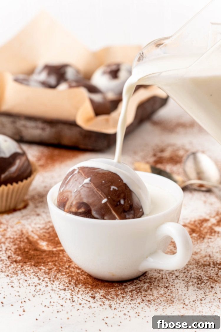Milk being poured into a white mug with a hot cocoa bomb.