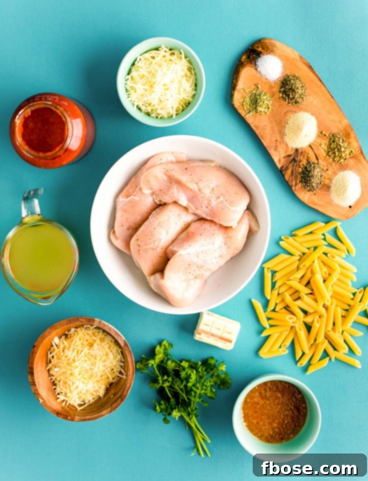 Overhead photo of all the ingredients for Instant Pot Chicken Parmesan Pasta neatly prepped on a teal background.