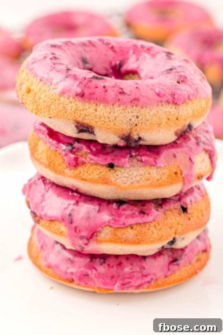 Close up photo of a stack of four blueberry donuts on a marble plate.