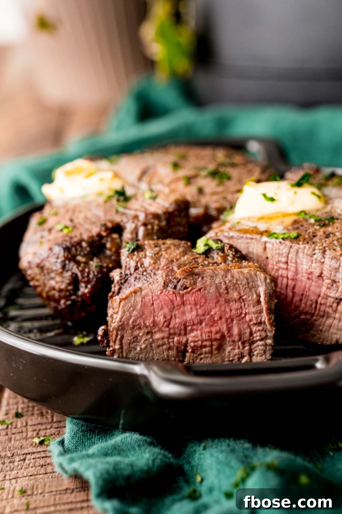Close up photo of a piece of steak sliced showing a pink center with the rest of the steak behind it on the plate.
