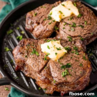 Two steaks on a black plate on a green napkin.