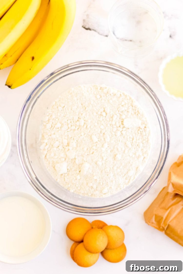Ingredients to make banana pudding poke cake on a white surface.