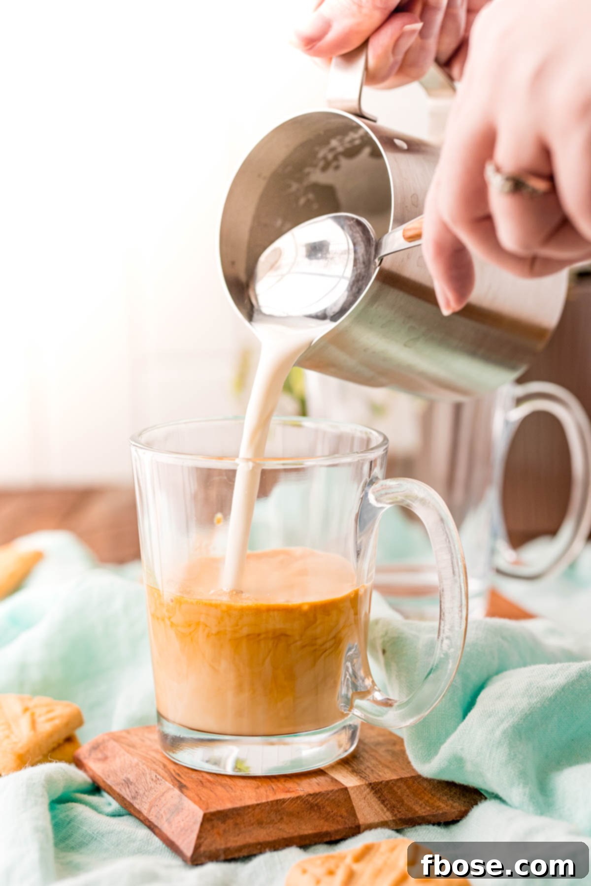 Breve Latte 5 A woman pouring steamed milk into a glass mug with espresso.