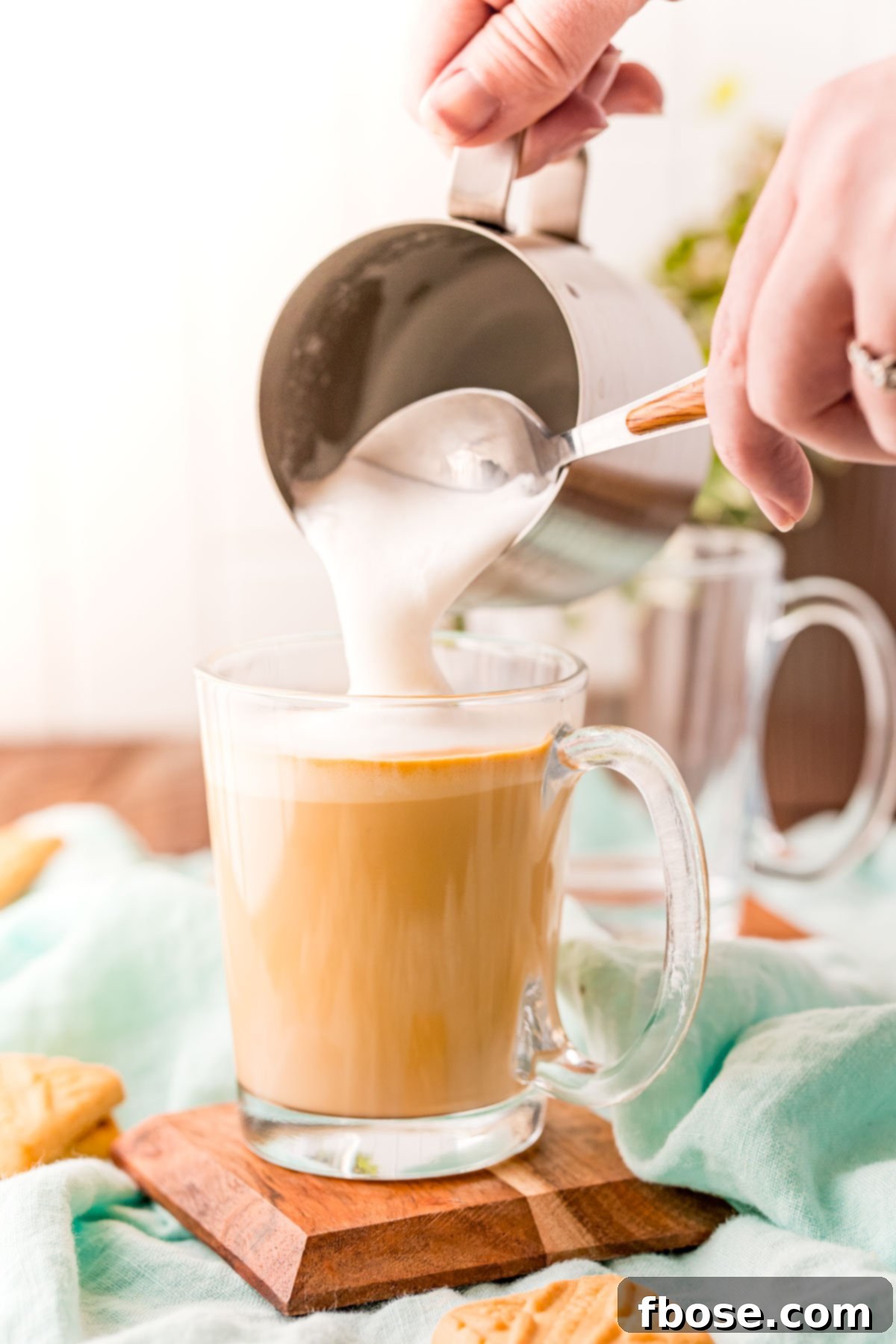 Breve Latte 6 A woman's hand scooping foam out of a milk steaming pitcher onto a latte.