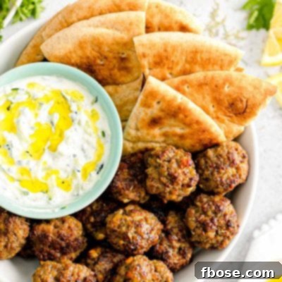 Overhead close up photo of Greek meatballs in a bowl with pita bread and tzatziki sauce.