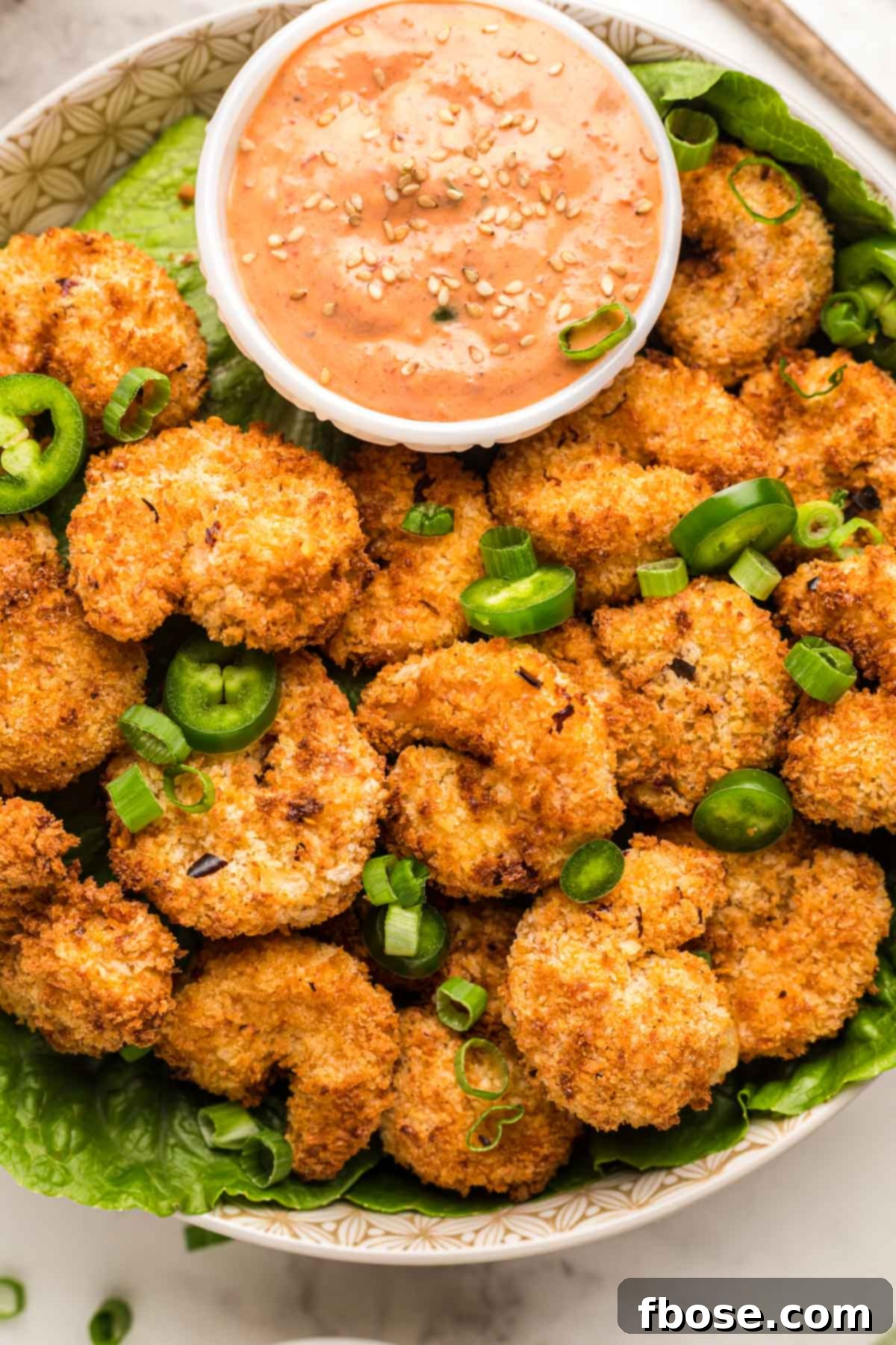 Overhead photo of a bowl filled with crispy air fryer shrimp with a dipping sauce.