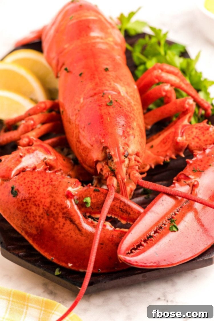 Close up photo of a cooked red lobster on a cutting board with herbs and lemon.