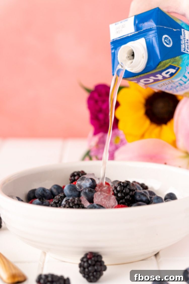Coconut water being poured into a bowl with fresh berries and ice to make Nature's Cereal.