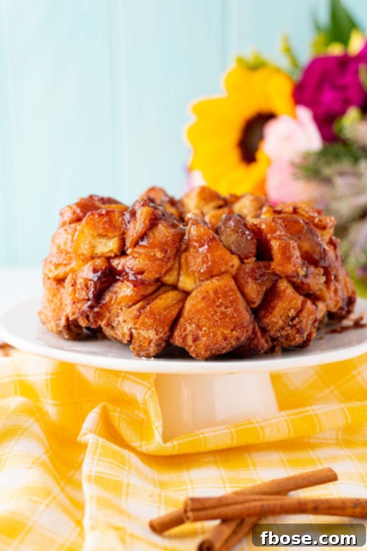 Close up photo of golden brown monkey bread on a elegant white cake stand, showcasing its sweet, crisp texture.