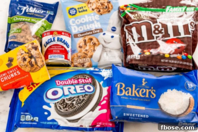 Packages of walnuts, sweetened condensed milk, Oreos, chocolate chunks, coconut, M&Ms, and cookie dough on a white table.