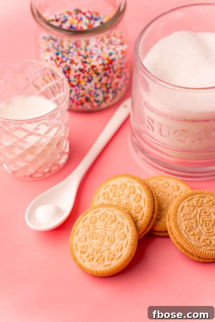 Golden Oreo Confetti Mug Cake 4 Ingredients to make a mug cake with golden Oreos on a pink surface.