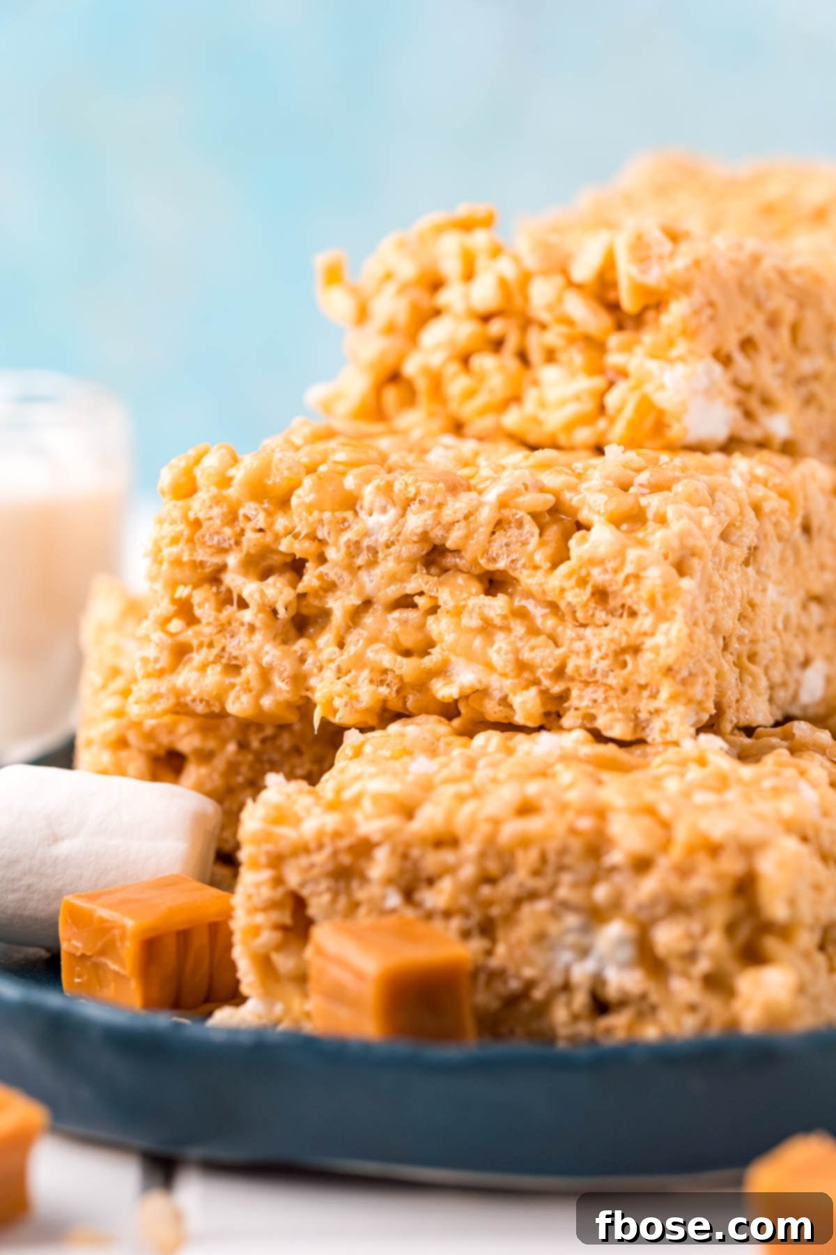 Salty-Sweet Caramel Crunch Bars 3 Salted caramel rice krispie treats stacked on a blue plate.