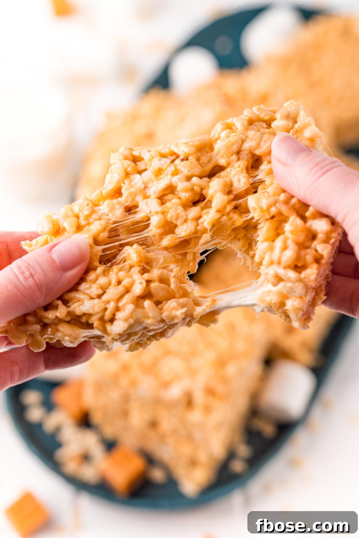 Salty-Sweet Caramel Crunch Bars 7 Caramel rice krispie treat being pulled apart by a woman's hands.