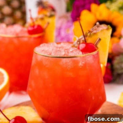 Close up photo of a bahama mama cocktail garnished with a maraschino cherry and pineapple wedge.