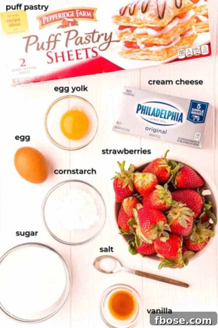 Ingredients laid out on a table, including fresh strawberries, puff pastry, cream cheese, and other baking essentials for danishes.