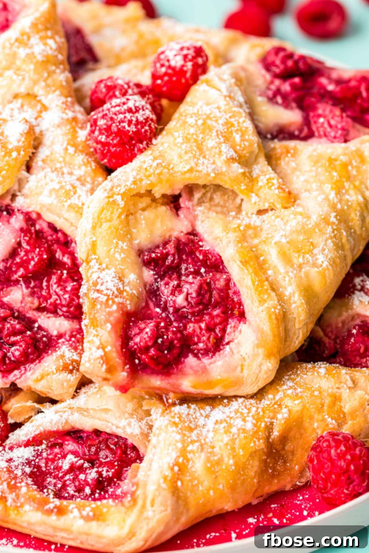 Close up photo of raspberry danishes piled on a plate.