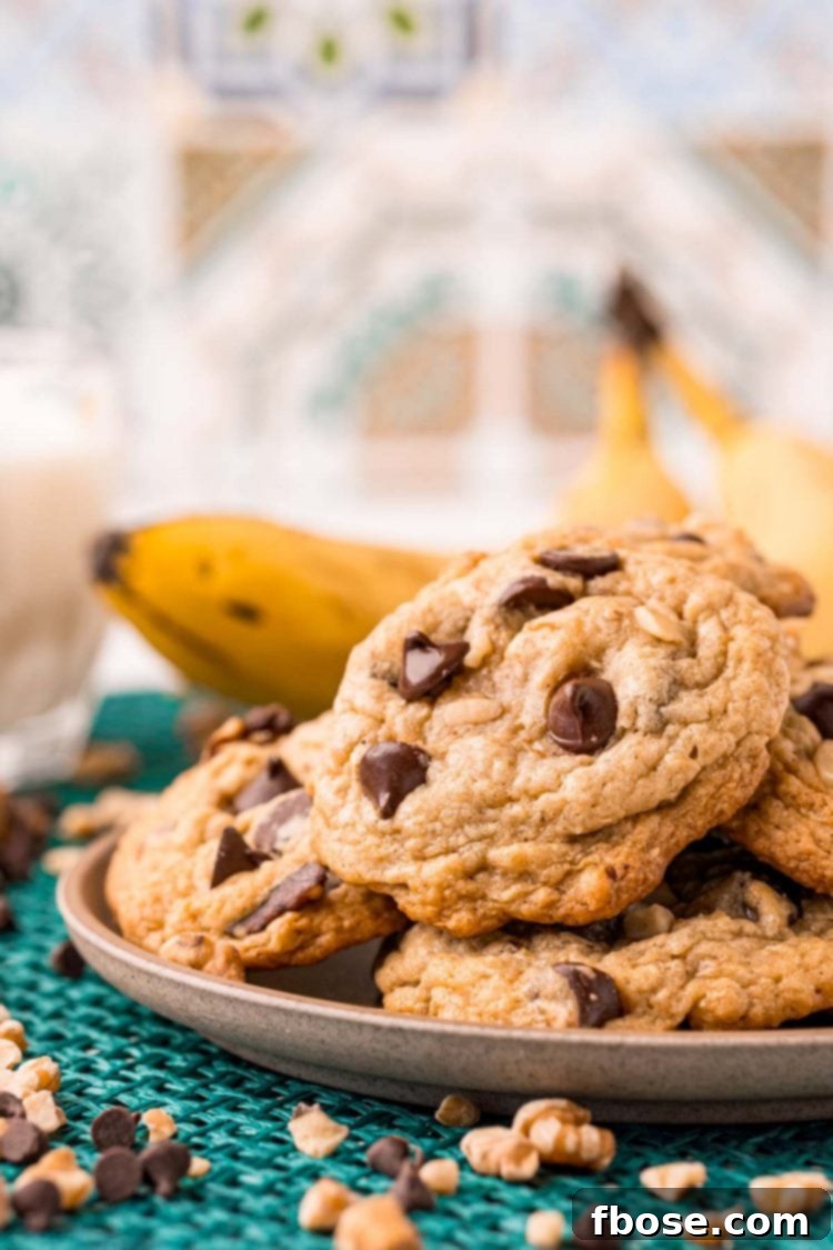 Ultimate Banana Bread Cookies 3 Banana bread cookies on a small plate on a teal placemat with bananas in the background.