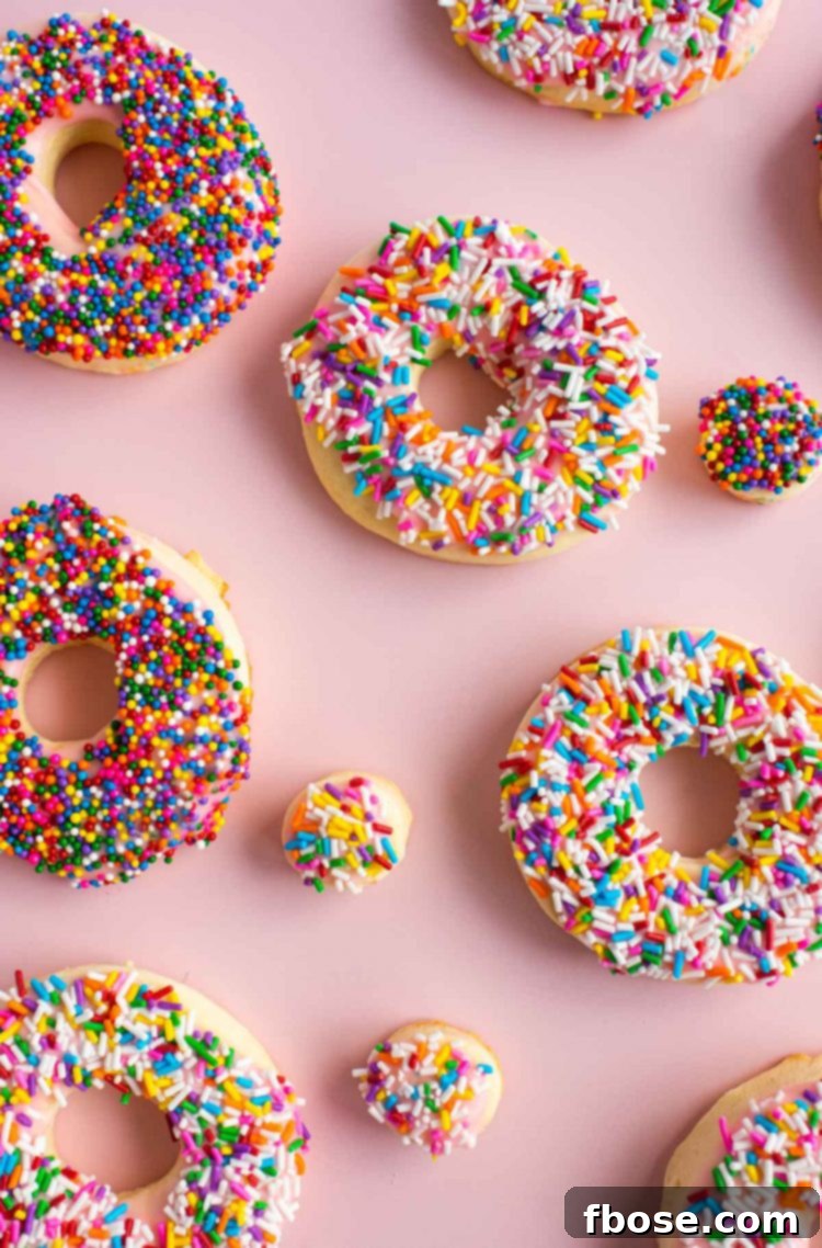 Overhead photo of donut cookies spread out on a pink surface.