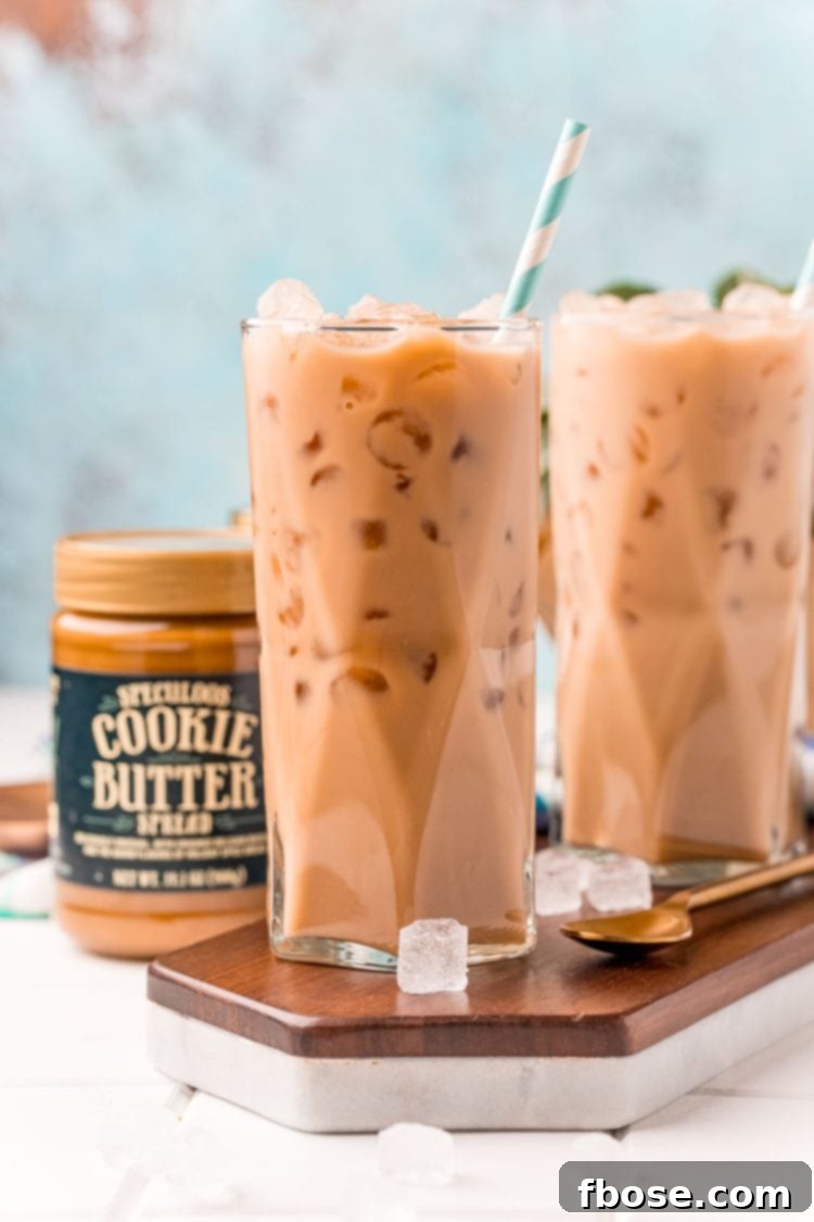 The Viral TikTok Starbucks Secret Cookie Butter Latte 3 Straight on photo of two glasses filled with iced cookie butter lattes and a jar of cookie butter next to it.