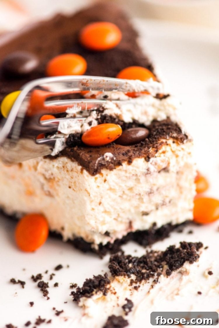 Close up photo of a no bake peanut butter cheesecake on a white plate with a fork cutting a piece off.