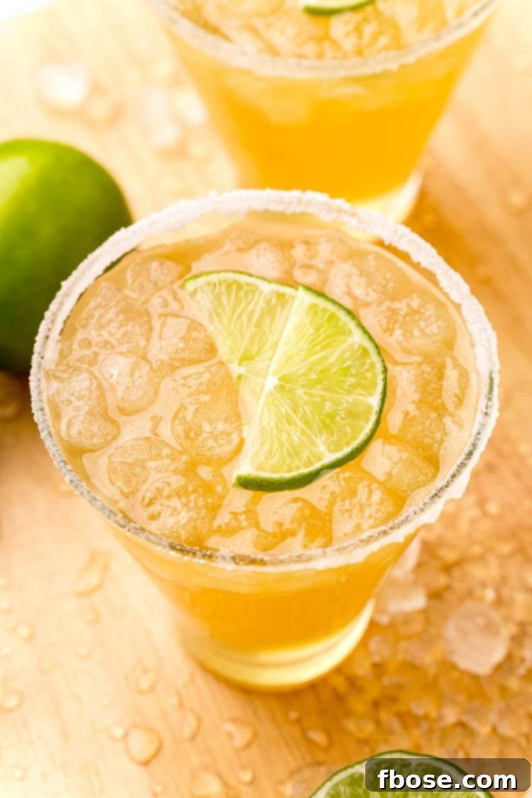 Close-up photo of a glass filled with a Beer Margarita, expertly rimmed with sugar and garnished with fresh lime wedges, ready to be enjoyed.