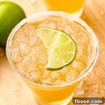 Close up photo of a glass with a beer margarita in it rimmed with sugar and garnished with lime wedges.