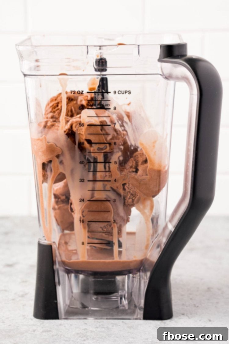 Ingredients for chocolate milkshakes, including chocolate ice cream and chocolate milk, loaded into a high-speed blender, ready for the blending process.