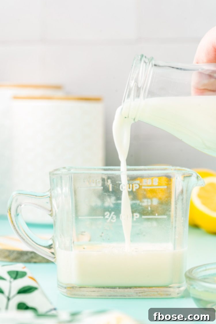 Milk being poured into a glass measuring cup.