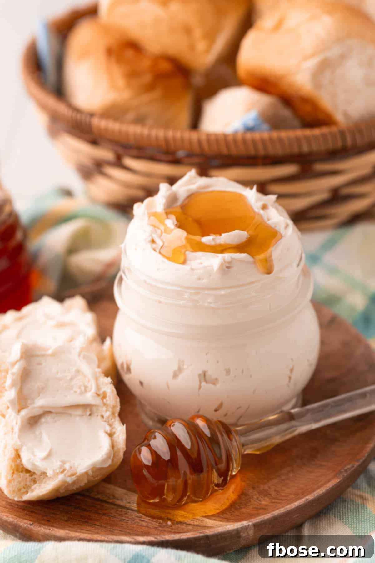 A jar filled with whipped honey butter on a wooden plate, ready to be served.