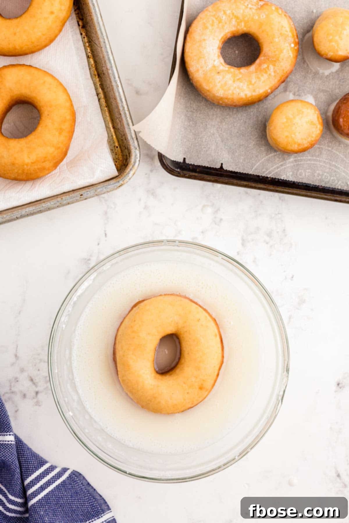 Sourdough donuts being dipped in glaze.