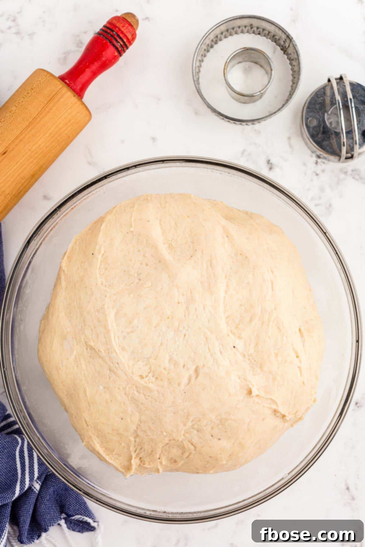 Donut dough proofed in a glass bowl.