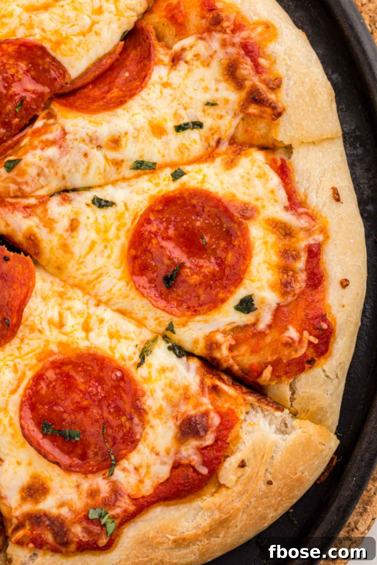 Perfect Sourdough Pizza Dough 2 Overhead photo of a freshly baked sourdough pizza, golden brown and topped with melted cheese, resting on a pizza stone.